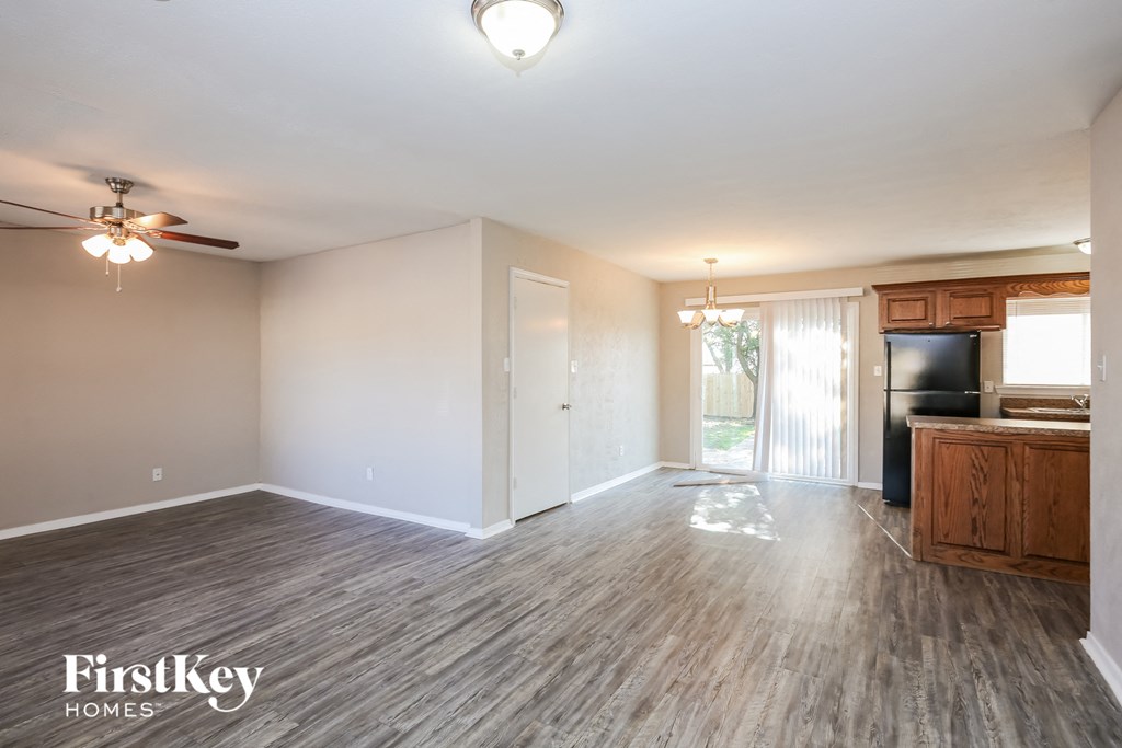 the living room and kitchen of an empty house with wood flooring