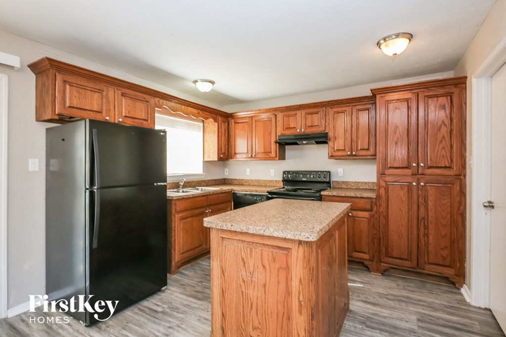 a kitchen with wooden cabinets and a black refrigerator