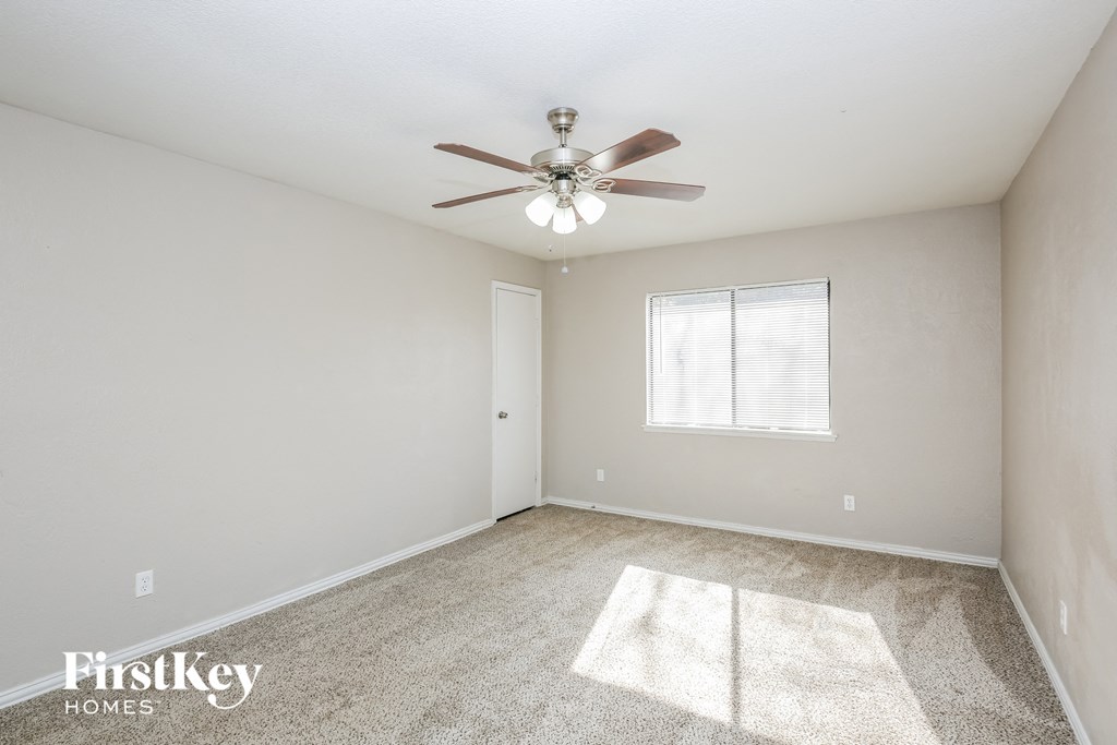 the spacious living room with ceiling fan and carpet