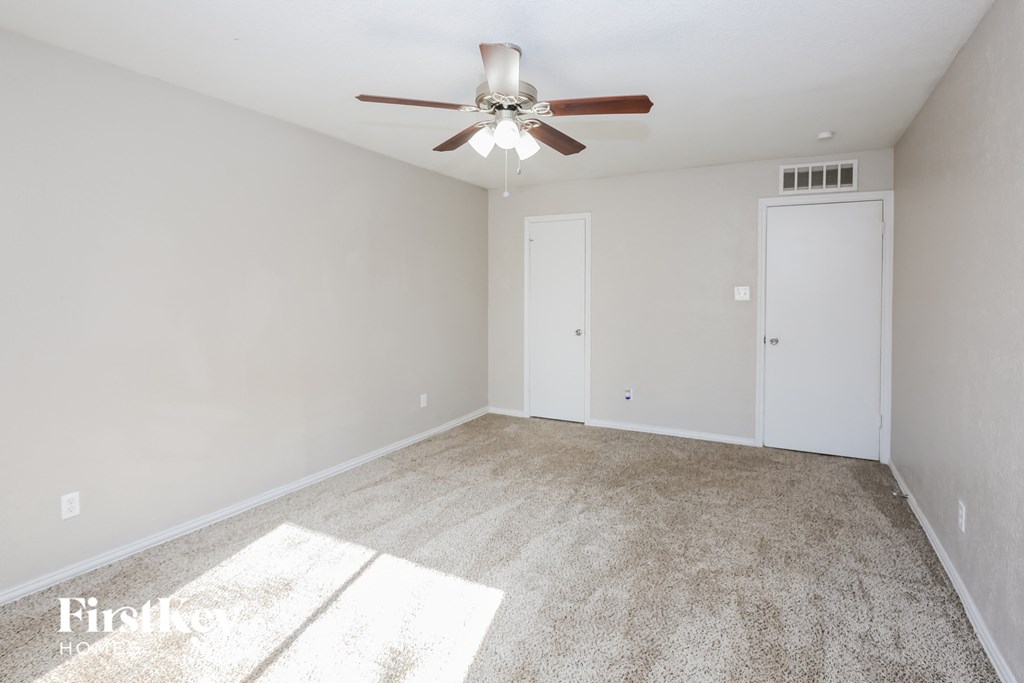 a empty living room with a ceiling fan and white walls