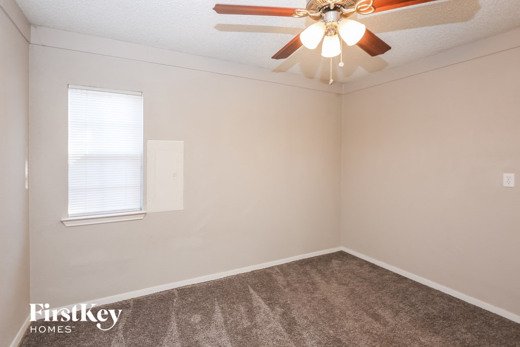 a bedroom with a ceiling fan and a carpet