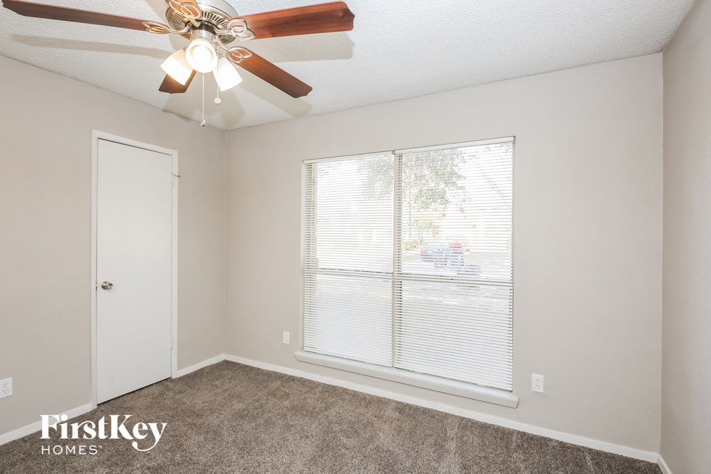 a bedroom with a ceiling fan and a large window