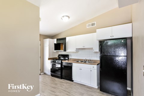 a kitchen with white cabinets and black appliances and a black refrigerator
