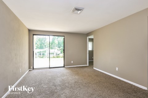 a living room with carpet and a sliding glass door