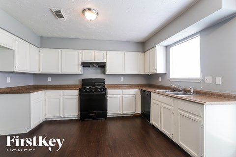 A kitchen with white cabinets and a black dishwasher.
