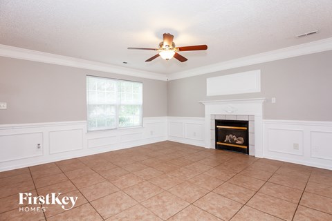 A spacious living room with a fireplace and a ceiling fan.