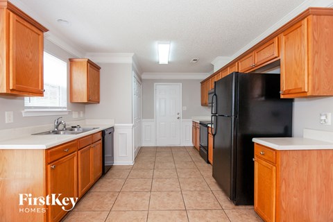A kitchen with wooden cabinets and a black refrigerator.