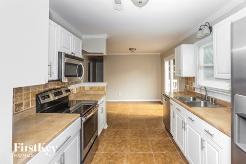 A kitchen with white cabinets and a tiled floor.
