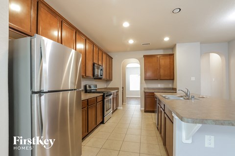 A kitchen with a refrigerator, sink, and cabinets.