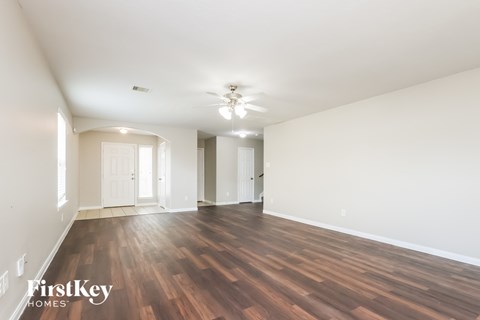 A spacious room with wooden floors and white walls.