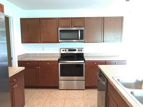 A kitchen with brown cabinets and a stainless steel refrigerator.