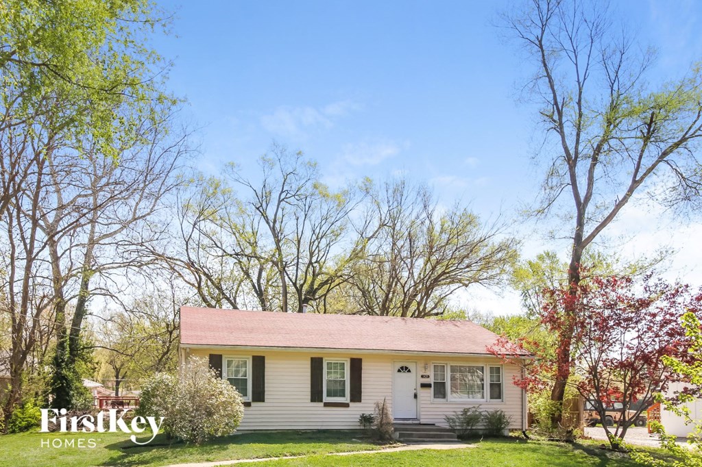a small white house with a red roof and some trees
