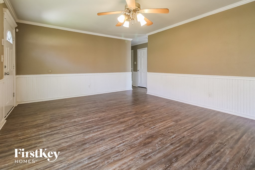 an empty living room with wood floors and a ceiling fan