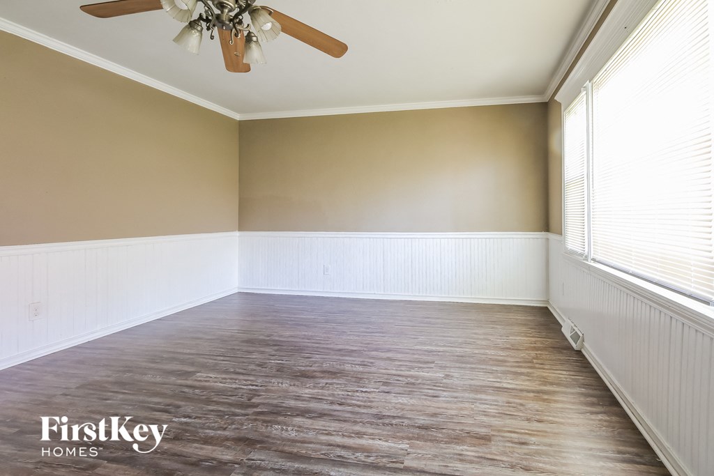an empty living room with wood floors and a ceiling fan