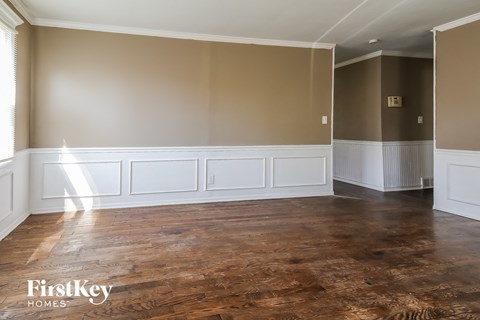 a living room with a wood floor and a wall with white wainscoting
