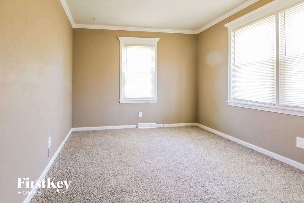 a empty room with two windows and a carpeted floor
