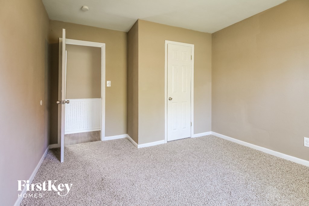 a bedroom with a white door and a carpeted floor