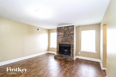 a living room with a stone fireplace and wooden floors