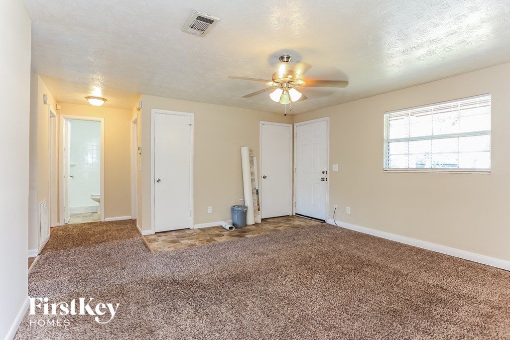 A room with a carpeted floor and a ceiling fan.