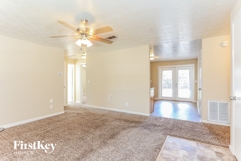 A spacious room with a carpeted floor and a ceiling fan.