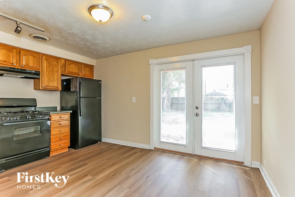 A kitchen with wooden cabinets and a black fridge.