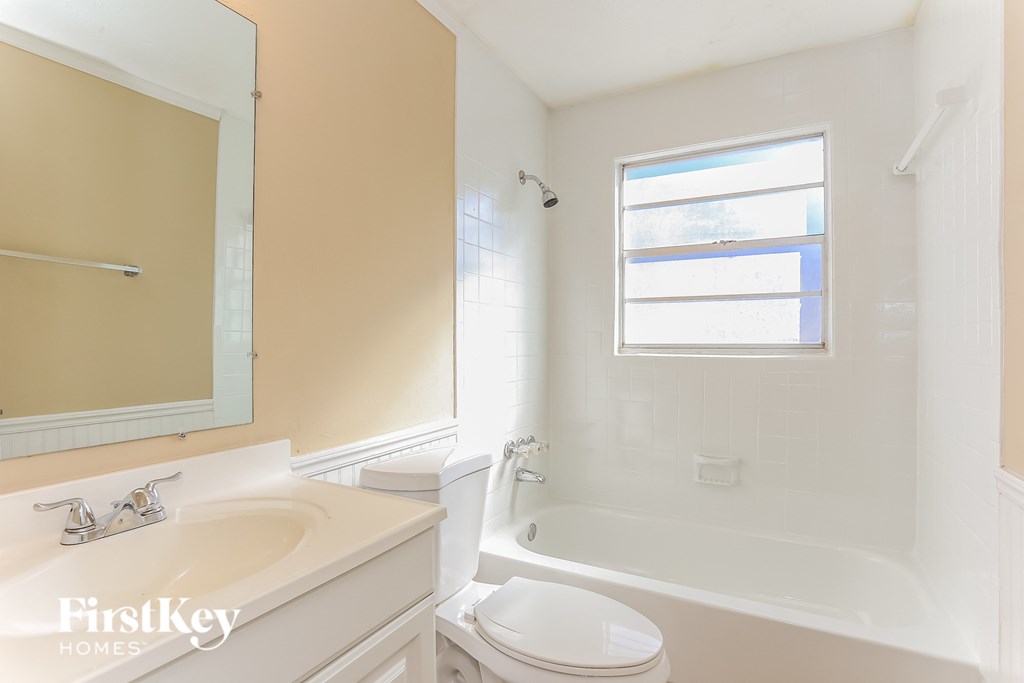 A white toilet sits next to a bathtub in a bathroom.
