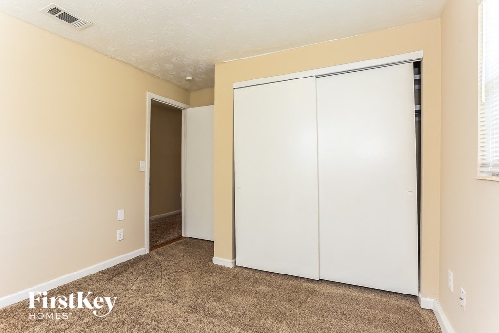 A bedroom with a white closet and a carpeted floor.