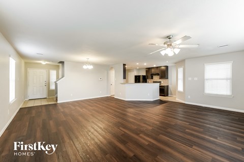 A spacious room with wooden flooring and a ceiling fan.