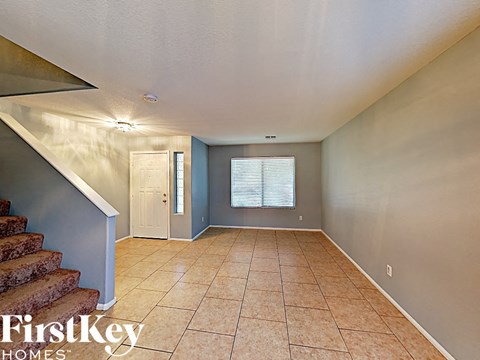 an empty living room with a staircase and tiled floors
