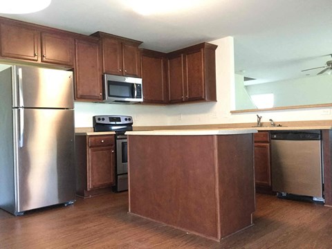 A kitchen with wooden cabinets and a stainless steel refrigerator.
