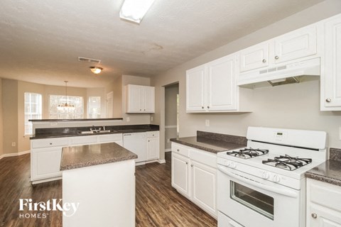 A kitchen with white cabinets and a white stove top oven.
