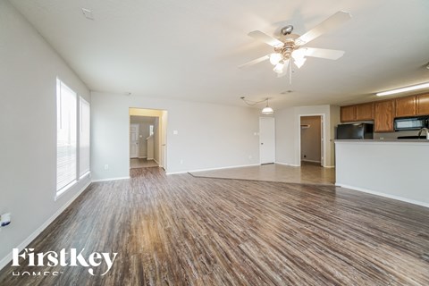 an empty living room with wood flooring and a ceiling fan
