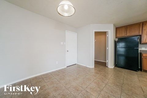 a kitchen with a black refrigerator and tile flooring
