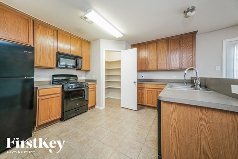 a kitchen with wooden cabinets and black appliances and a sink