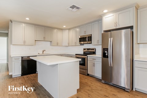 A kitchen with white cabinets and a stainless steel refrigerator.