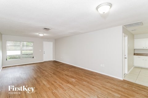 the living room and dining room with wood flooring and white walls