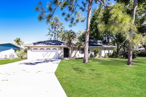 a white house with a lawn and palm trees