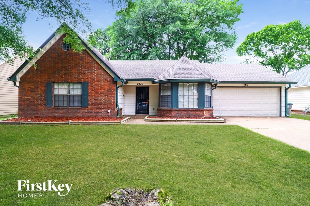 front view of a brick house with a yard and grass
