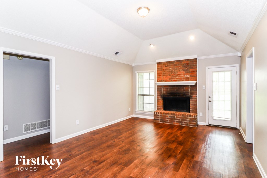 the living room with wood floors and a brick fireplace