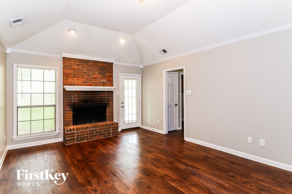a living room with a brick fireplace and wooden floors