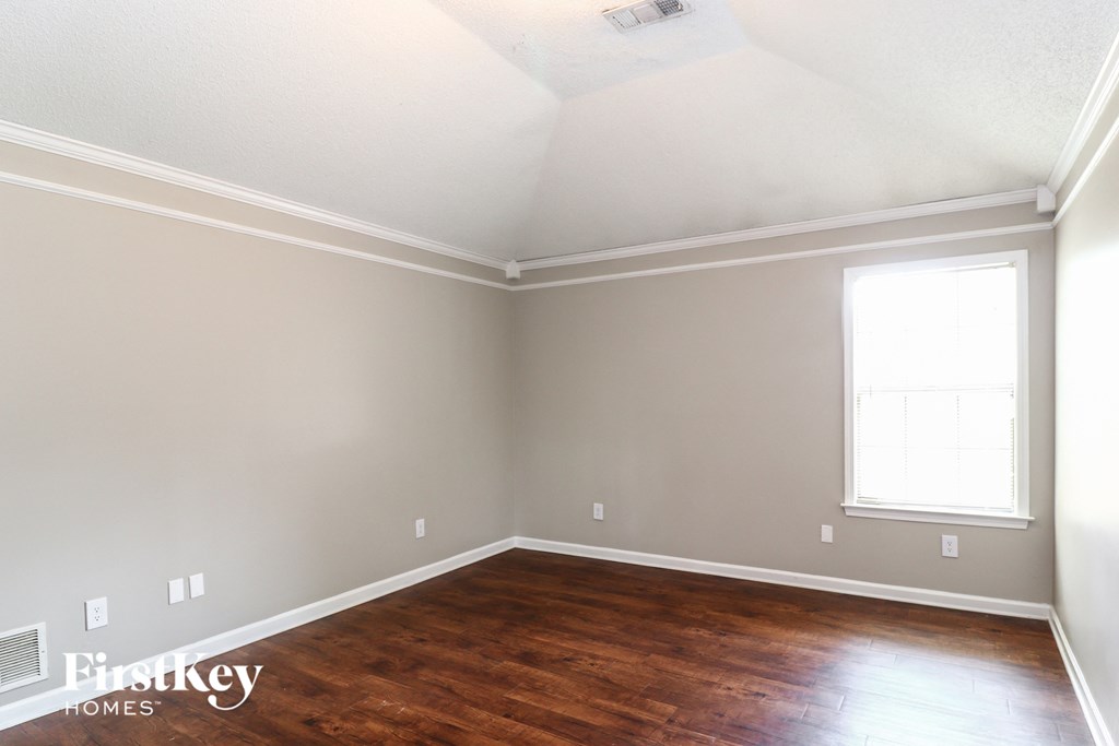 the living room of a home with wooden floors and a window