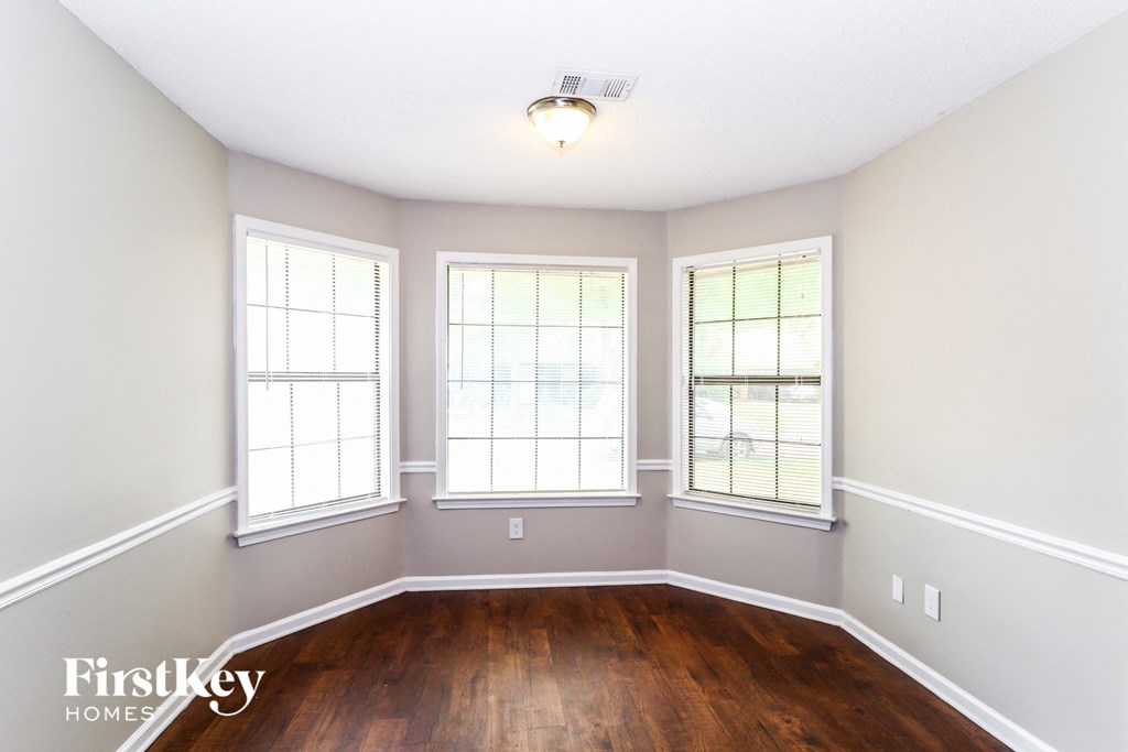 a dining room with wood floors and three windows