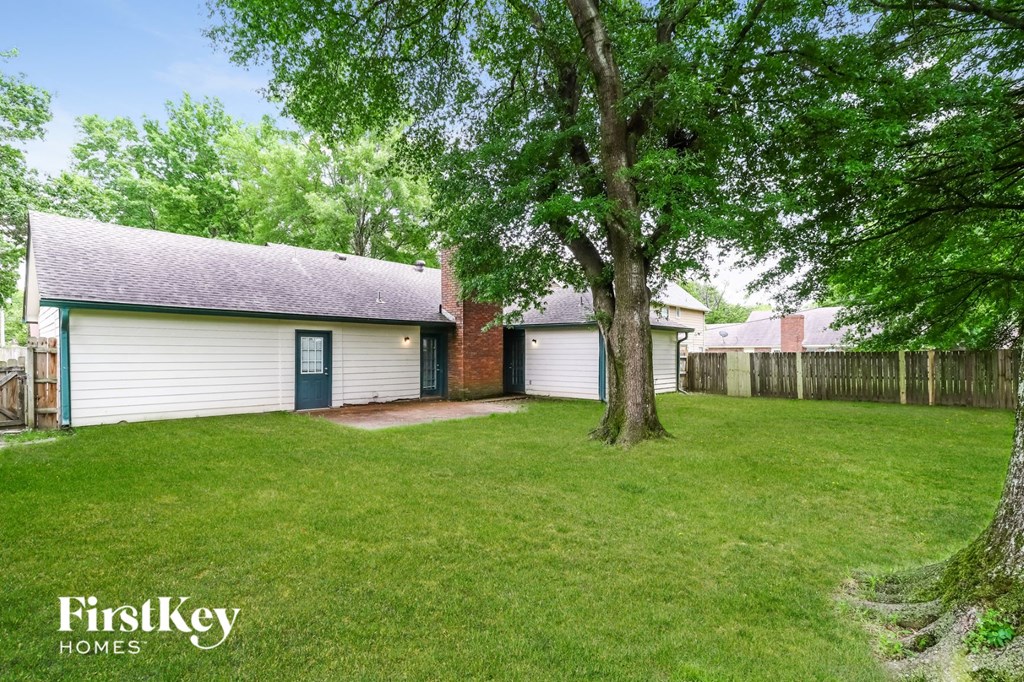 a backyard with a tree and a white house