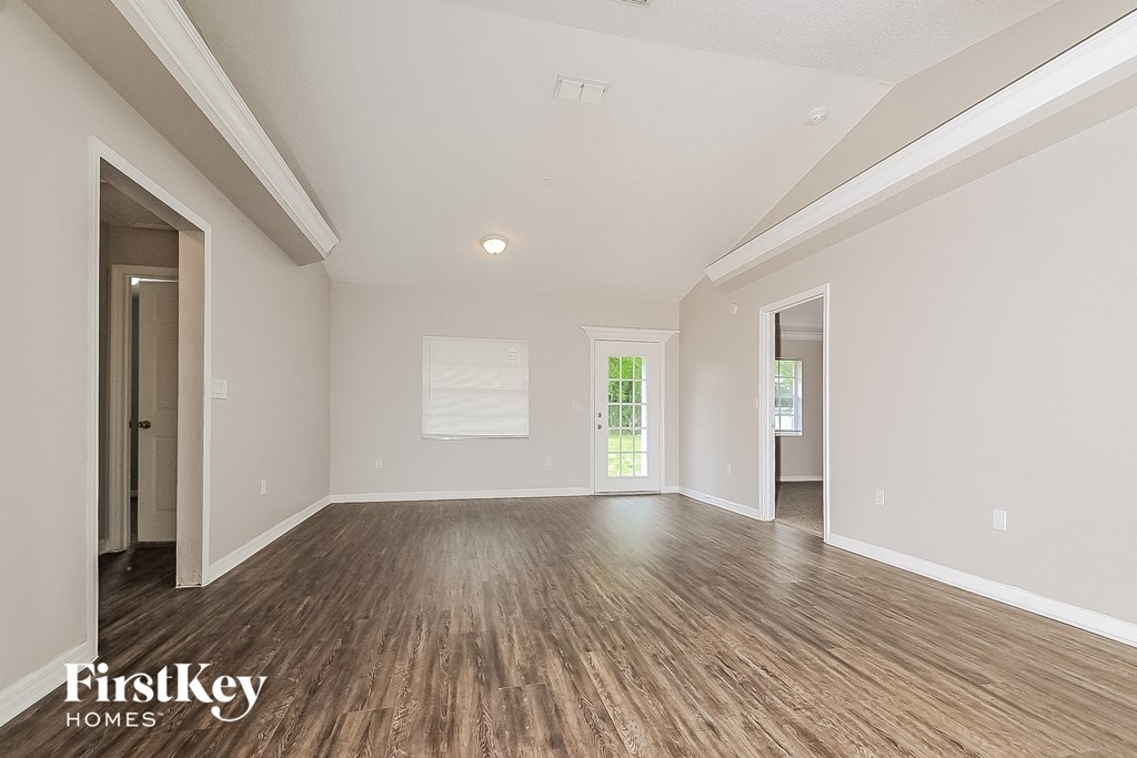 A spacious room with wooden floors and white walls, branded with "FirstKey Homes".