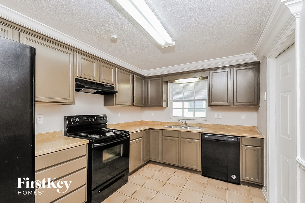 A kitchen with a black fridge and black dishwasher.