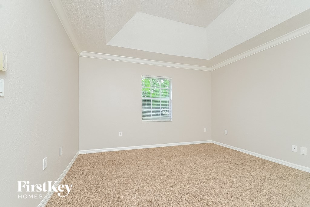 A room with a carpeted floor and a window with blinds.