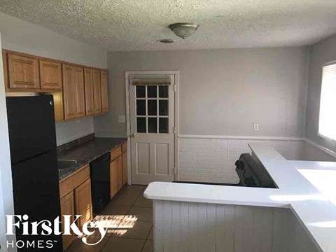 A kitchen with a black fridge and wooden cabinets.