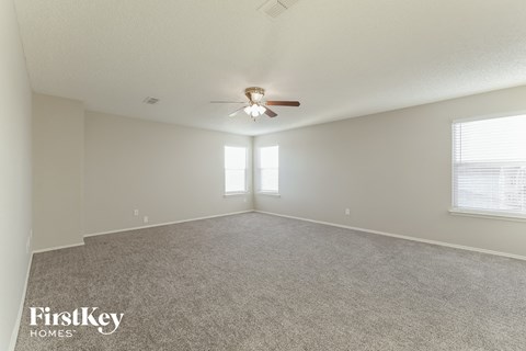 the spacious living room with ceiling fan and carpet