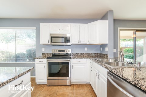 A kitchen with white cabinets and granite countertops.