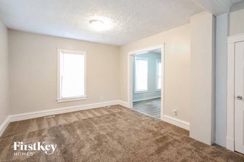 a living room with carpet and a door to a bedroom